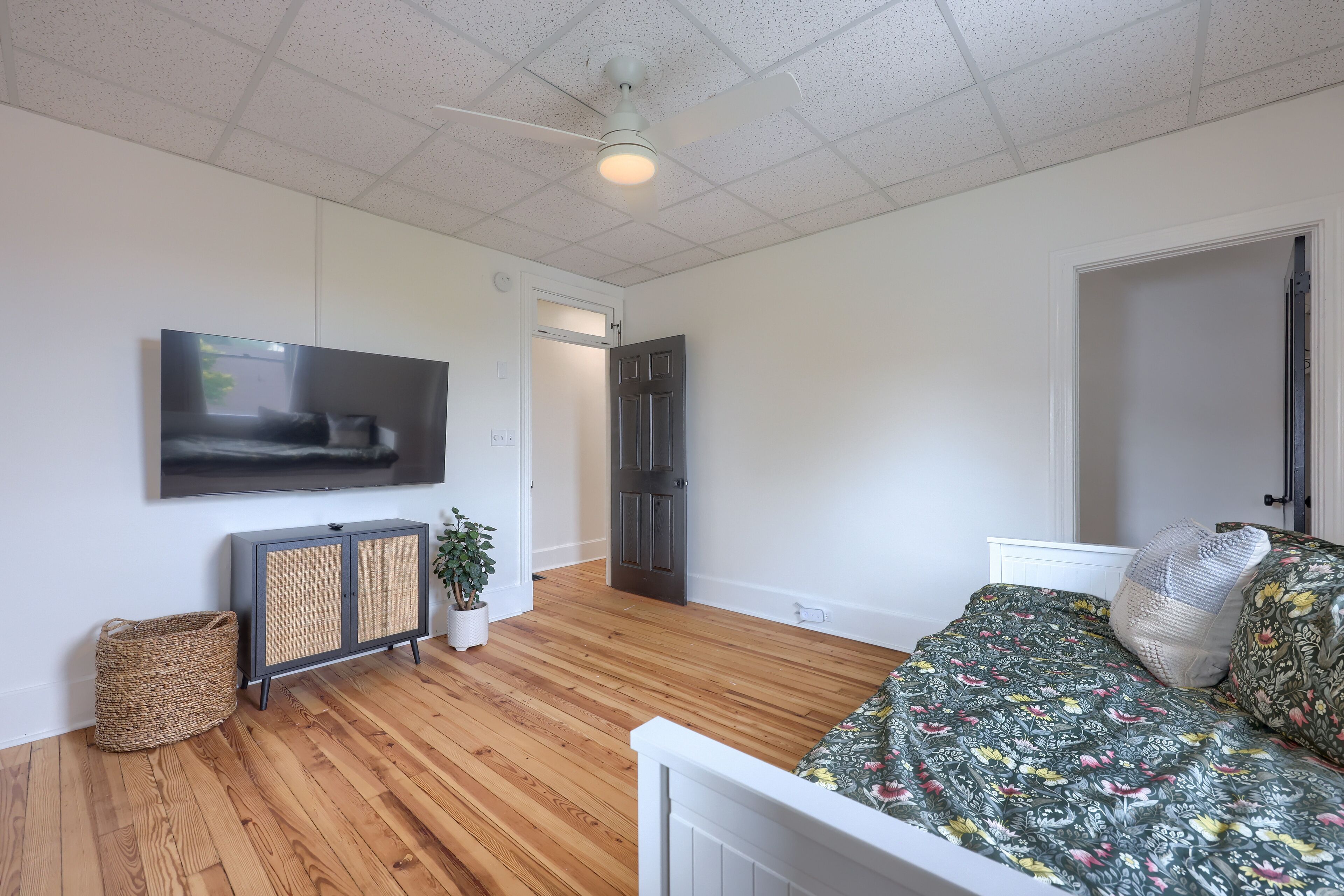 Un dormitorio con cama, televisor, armario y puerta.