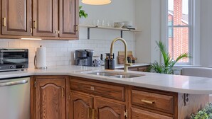 A kitchen with wooden cabinets, a built-in oven, a sink with a gold faucet, and pendant lighting.