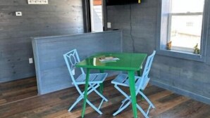 Een kamer met een groene tafel en blauwe stoelen, een raam met uitzicht en een tv aan de muur.