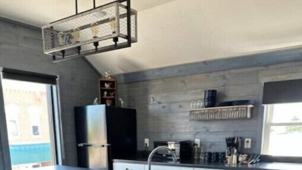 Een moderne keuken met een groot eiland, barstoelen, een spoelbak en een vuilnisbak.