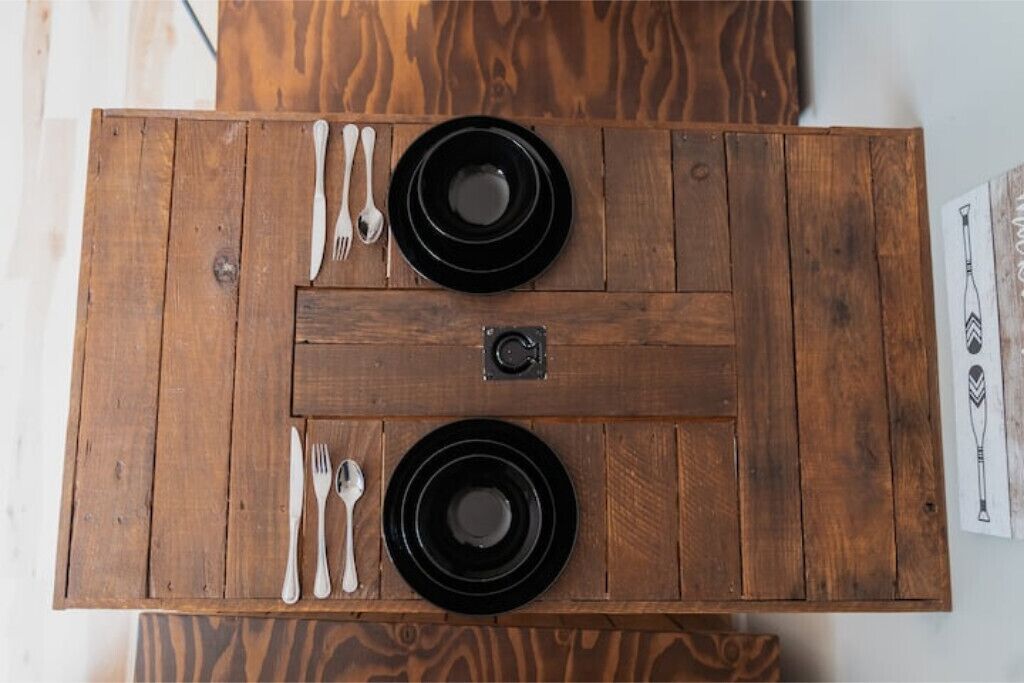 Una mesa de madera con dos platos negros y cubiertos.