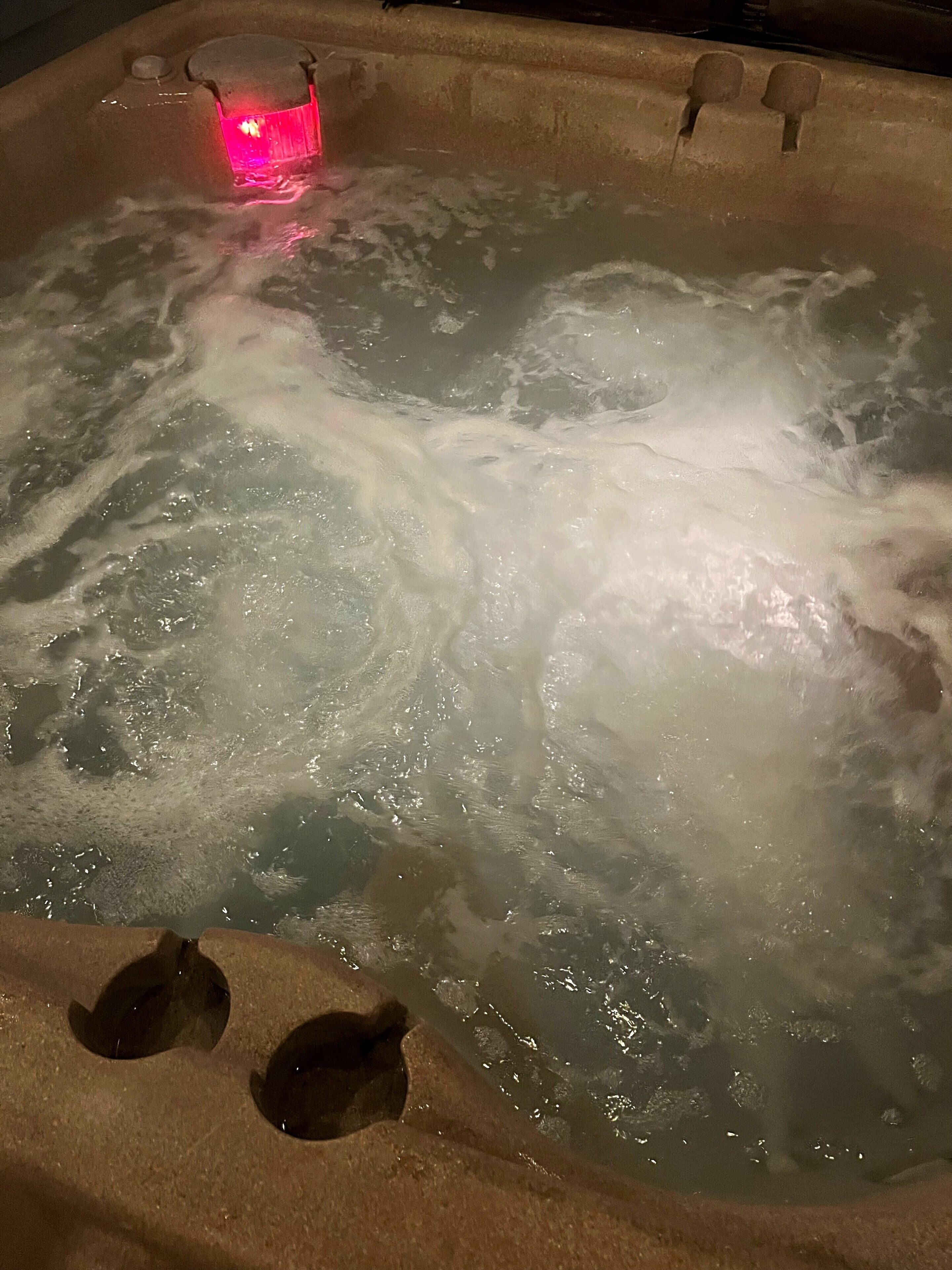 A hot tub with a visible pump and a red light.