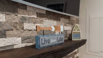 Un muro de piedra rústica con un letrero de madera que dice “Live love Lake” y una señal con una flecha direccional.