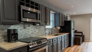 A modern kitchen with stainless steel appliances, a tiled backsplash, and wooden flooring. - Beaver Lake Escape
 (Rock Hill)