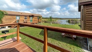 Eine Holzterrasse mit Picknicktisch und Blick auf einen See und Gebäude.