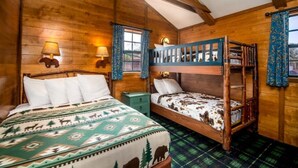 Una habitación estilo cabaña de madera con dos camas, una con una manta estampada y la otra con estampado de vaca. Hay vigas de madera en el techo y una ventana con cortinas.
