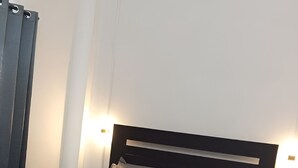A neatly made bed with a brown headboard, two bedside tables, and a blue bedspread. - Hotel Arda Bali (Negara)