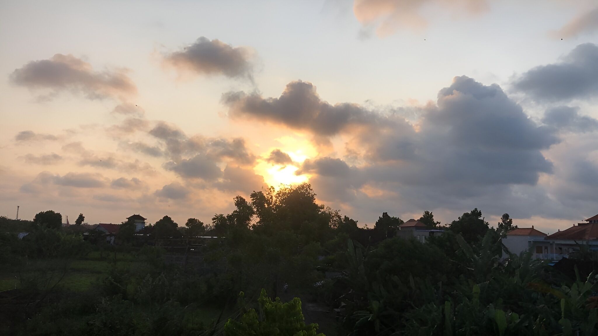 Atardecer sobre una zona residencial con casas y árboles.
