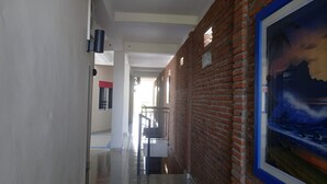 A corridor with a brick wall and a framed painting. - Hotel Arda Bali (Negara)