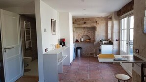 A kitchen with a brick wall, a white countertop, and a window. - Le Studio de Saint-maixent Le Petit (HAIMS)
