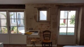 A room with a bed, a desk with a chair, a small table, and two windows. - Le Studio de Saint-maixent Le Petit (HAIMS)