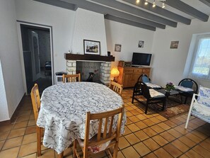 A dining area with a round table, chairs, a fireplace, a television, and a window.