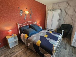 A bedroom with a bed, bedside tables, a wardrobe, and a chair.