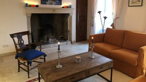 A living room with a fireplace, a sofa, a chair, and a table with candles. - La Biche - Bonnes - Gîte (BONNES)