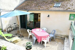 An outdoor seating area with a table and chairs, a bicycle, and a potted plant. - Gîte des 2 Frères - Saint-pierre-de-maille (SAINT-PIERRE-DE-MAILLE)