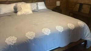 Une chambre dans une cabane en bois, avec un lit, une table de chevet et une chaise.