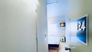 Un pasillo con una cama, un televisor y una puerta con el número 124.