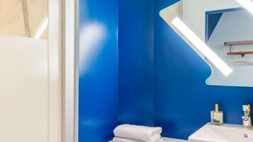 Un bagno con un lavandino bianco, uno specchio e una parete azzurra.