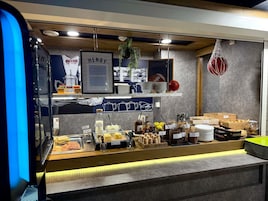 Una barra de desayuno con diversas opciones de comida y condimentos, un menú enmarco y una planta colgante.
