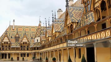 Une cour intérieure avec un bâtiment doté d’un toit orné de motifs et d’une galerie couverte.