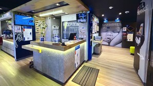 Un moderno vestíbulo de hotel con una recepción, un mural grande en la pared y un letrero que indica una zona de 'Cool Service'.