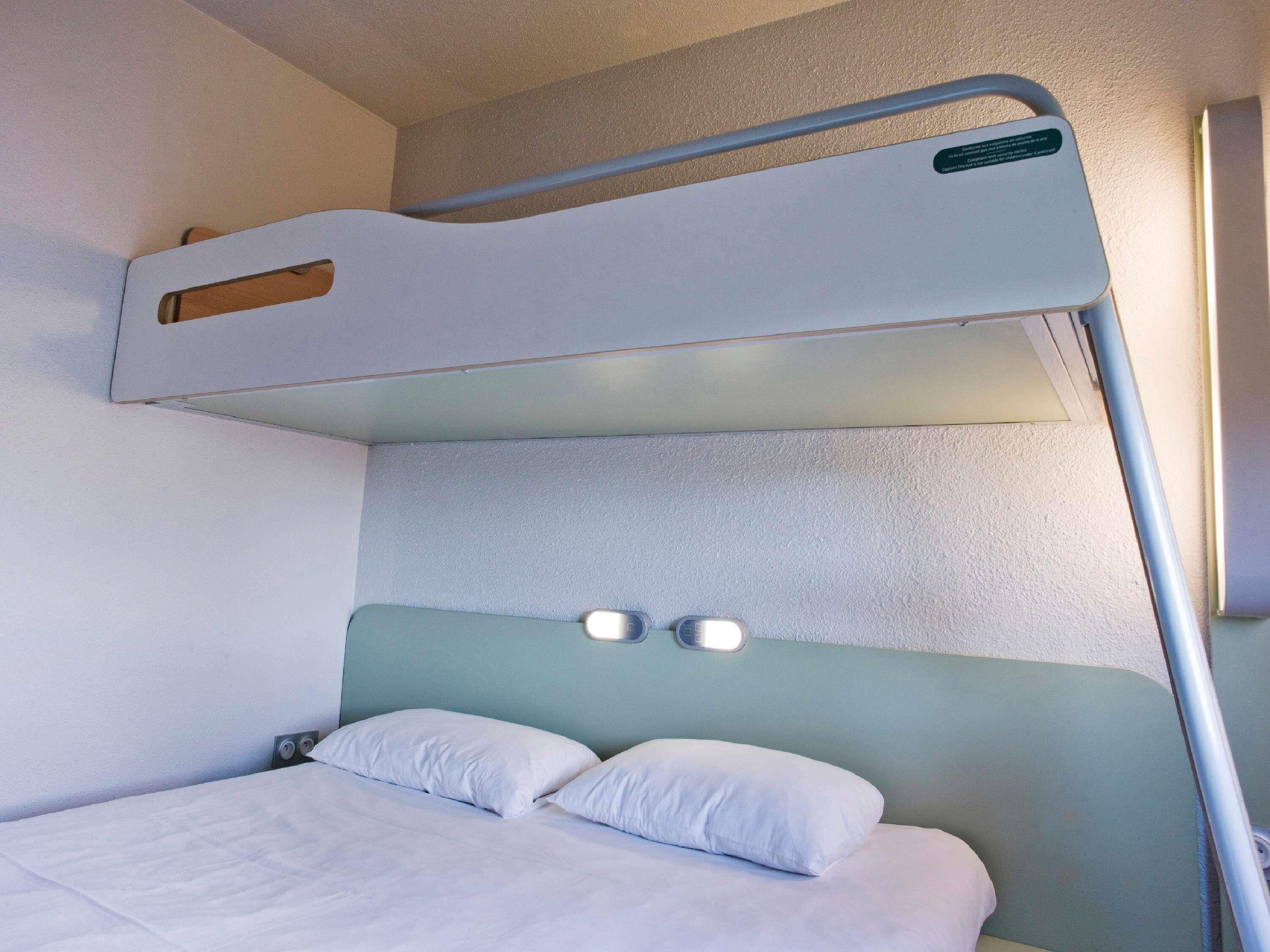 A bunk bed with a headboard and two bedside lamps.