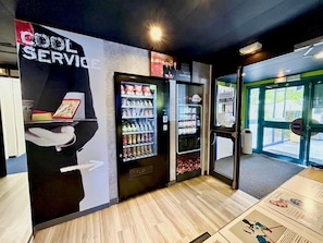 Un intérieur moderne avec un distributeur automatique, une affiche et une porte donnant sur l’extérieur.