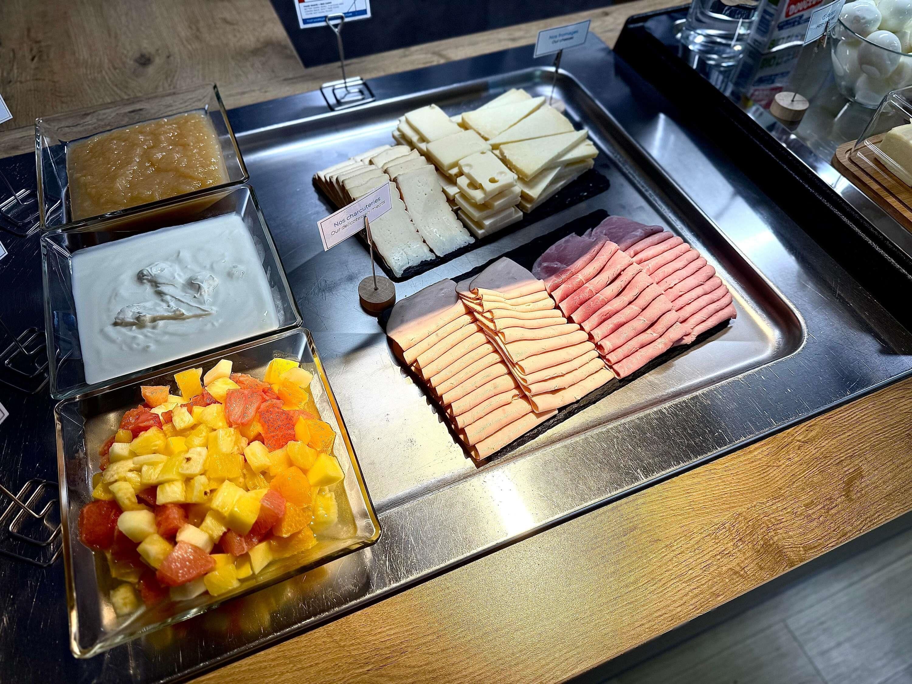 Un bufé con diversas opciones de comida, incluyendo frutas, quesos y embutidos.