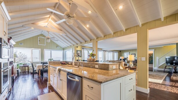 A spacious kitchen with a large island, wooden floors, and a ceiling fan. - Beautifully updated home on the bay and golf course with dock and raised deck! (Sodus Point)