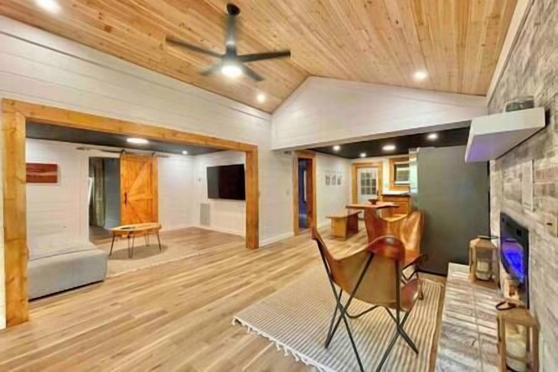 A spacious room with wooden flooring, a ceiling fan, and a dining area with a table and chairs.