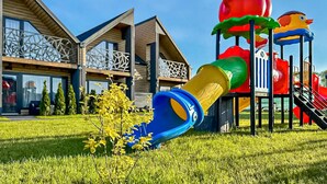 A playground with slides and climbing structures, a building with a modern design and balconies, and a well-maintained lawn. - Beach front home in Sarbinowo with sauna (Sarbinowo)