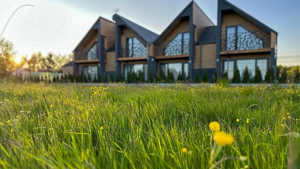 A modern house with a sloped roof and large windows, surrounded by a grassy field. - Beach front home in Sarbinowo with sauna (Sarbinowo)