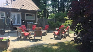 An outdoor patio area with Adirondack chairs and a grill.