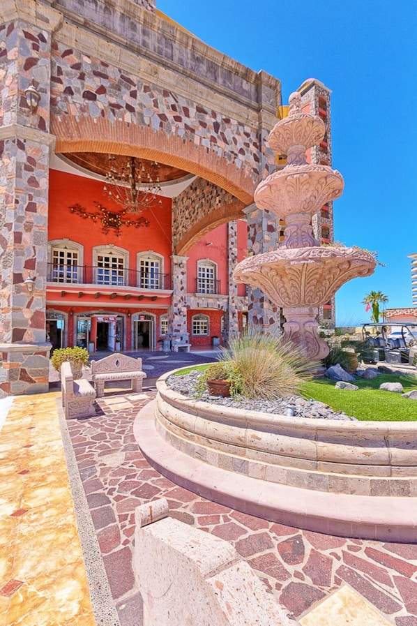 A historic building with a fountain, stone walls, and a courtyard.