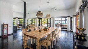 Un comedor amplio con una mesa y sillas de madera, ventanas grandes con cortinas y vistas al exterior.