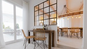 Een eetgedeelte met rieten stoelen, een houten tafel en een groot raam met uitzicht.