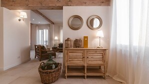 Een ruime woonkamer met een houten kast, twee spiegels aan de muur en een rieten mand op de vloer.
