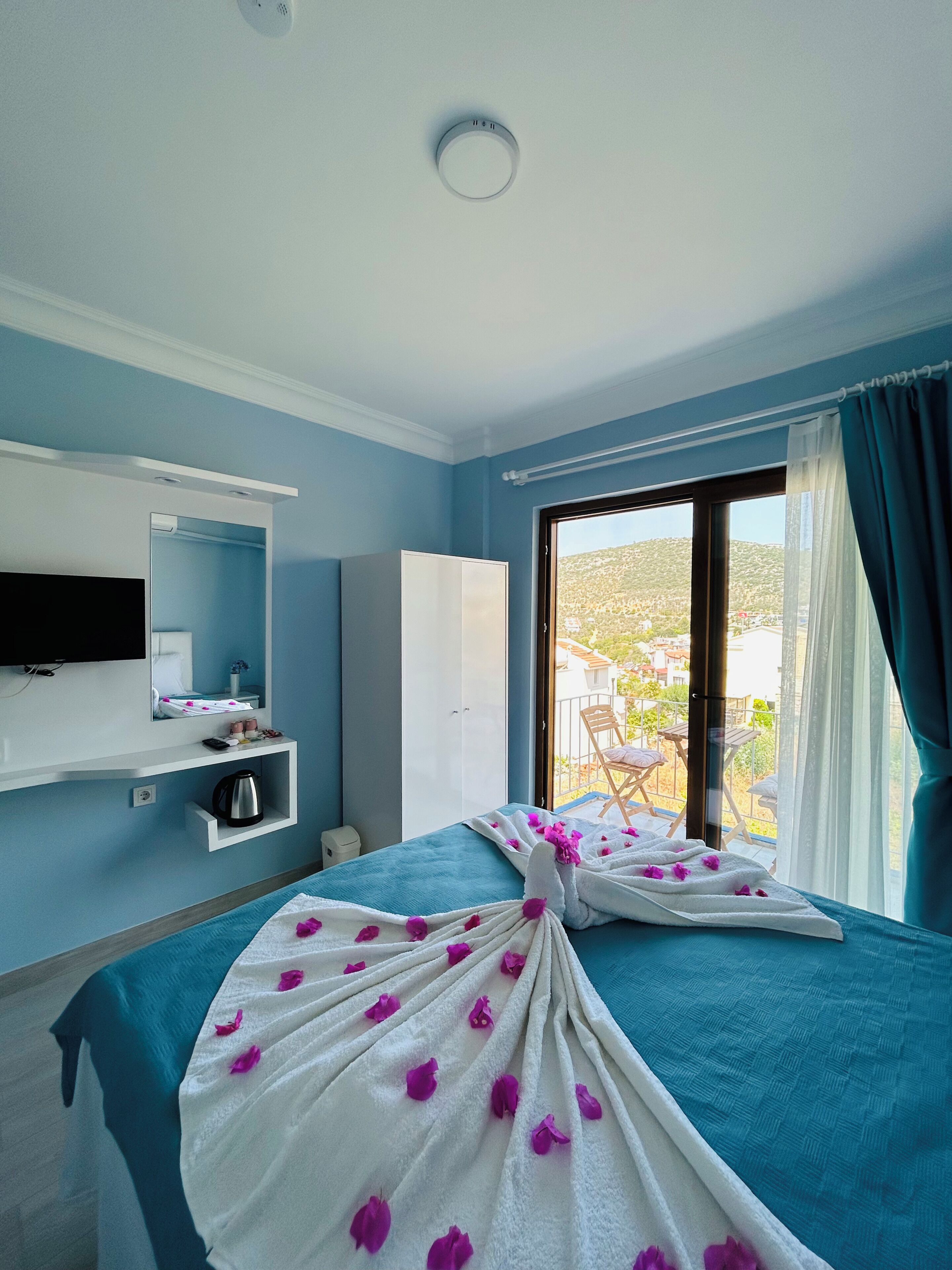 Quarto de hotel com cama, televisão, minibar e vista para o exterior.