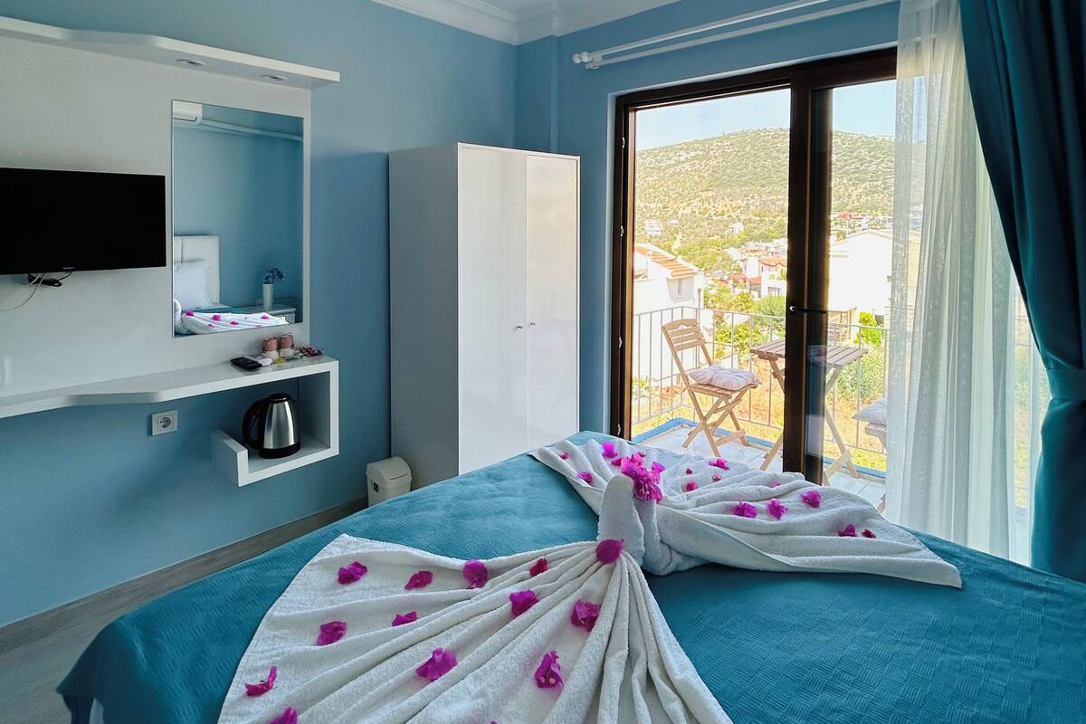 Een hotelkamer met een bed, een televisie, een minibar en uitzicht op het omliggende landschap.