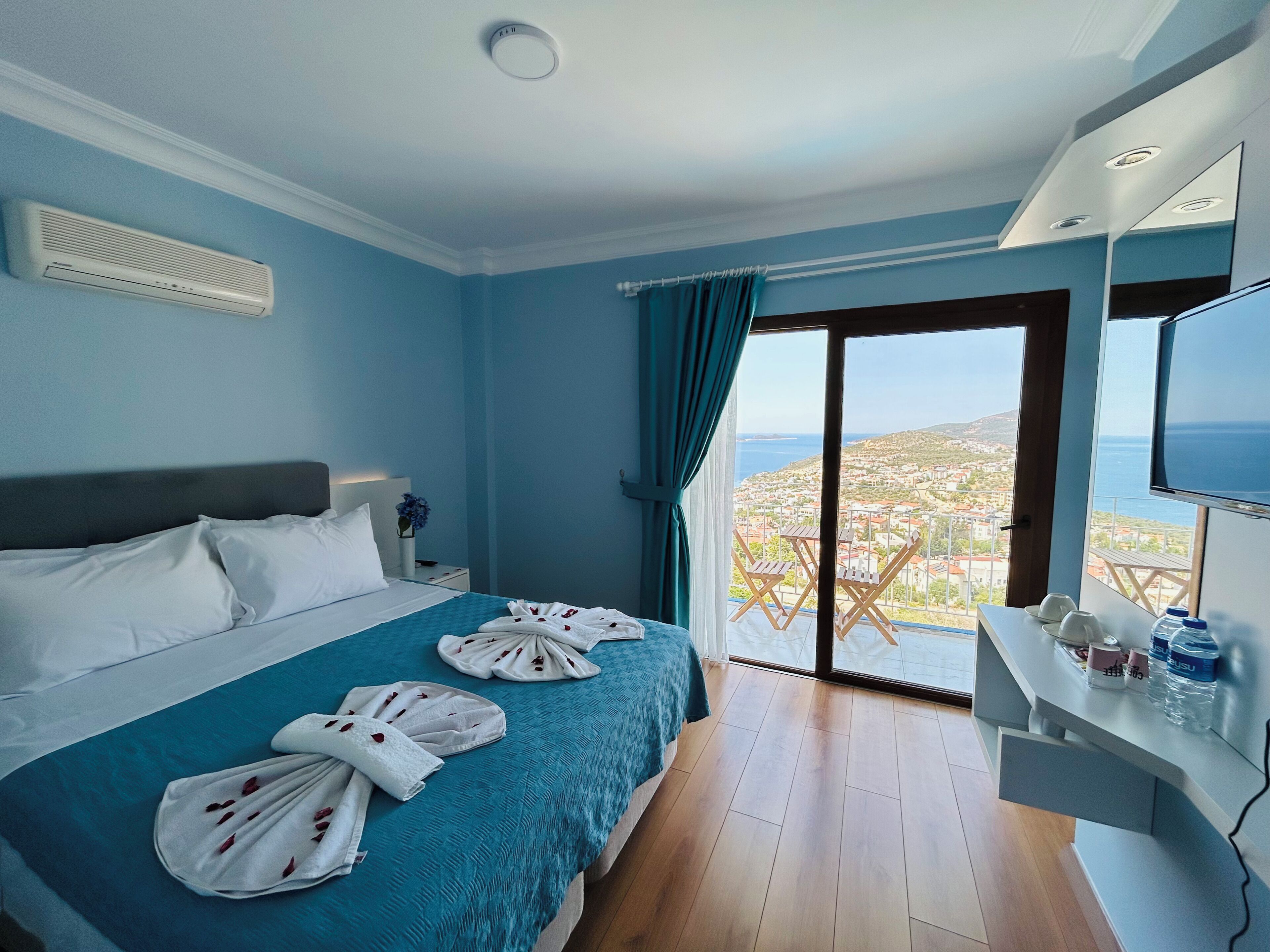 Quarto de hotel com cama, televisão e varanda com vista.