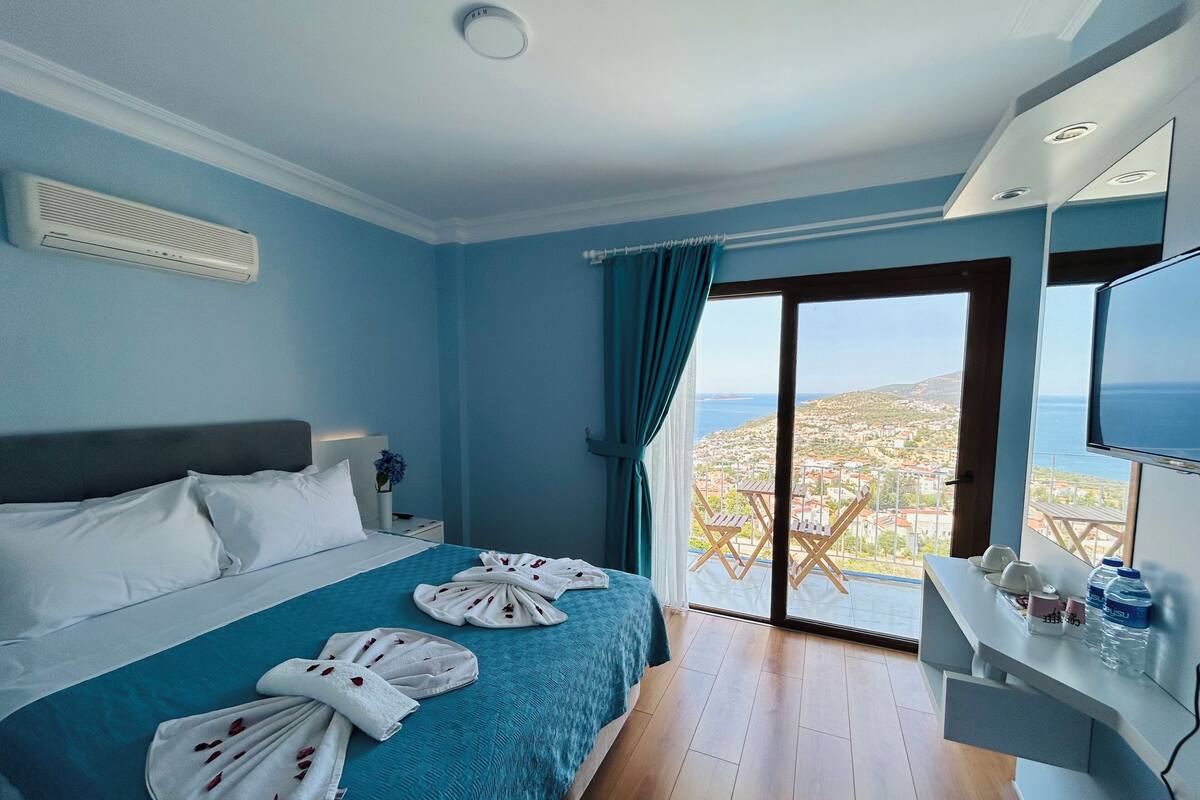 Een hotelkamer met een bed, een televisie en een balkon met uitzicht.