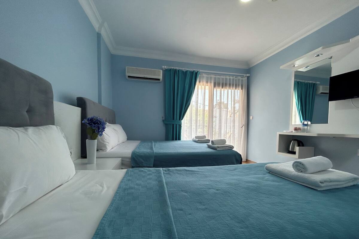 Een hotelkamer met twee bedden, een badkamer en een raam met gordijnen.