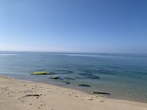A beach with clear water, visible footprints, and distant land. - La Maison aux Hortensias. Entre Campagne et Bord de mer (Trégunc)