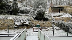 Un espacio exterior cubierto de nieve con un muro de piedra, un edificio pequeño y un sendero cercado.