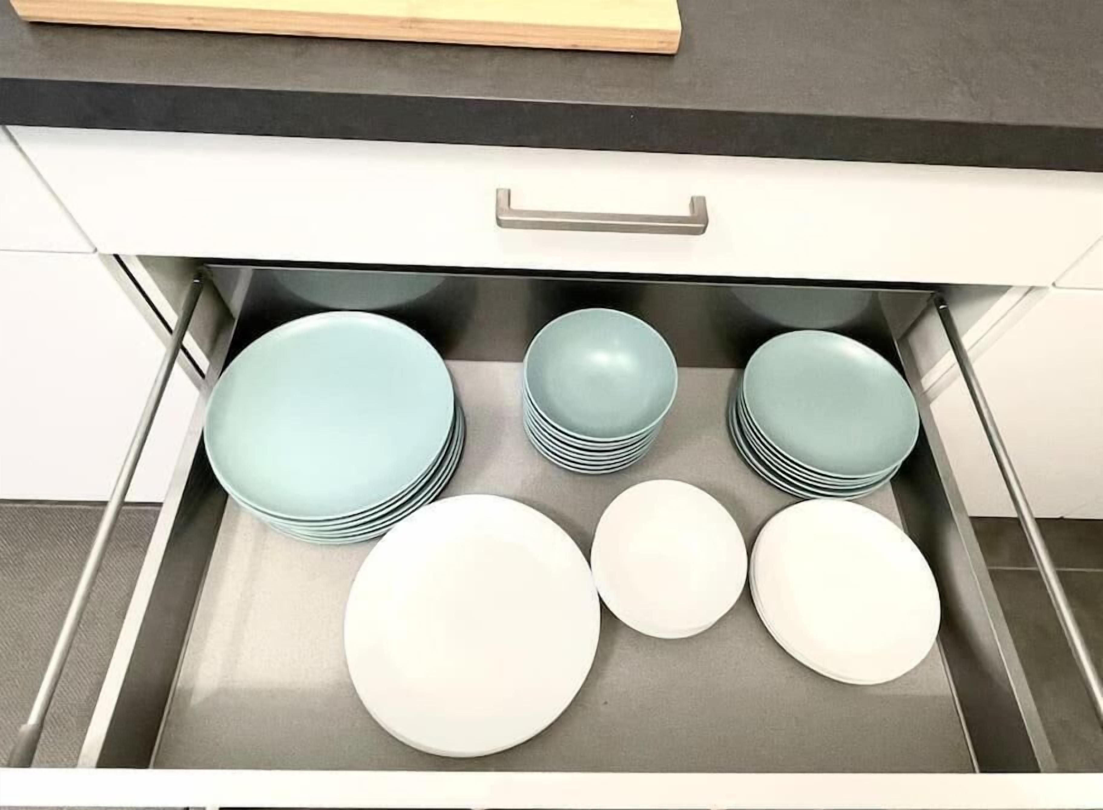 Un cajón de cocina con pilas de platos y tazones.