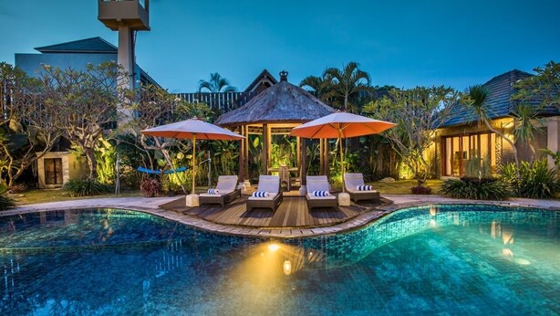 A swimming pool with lounge chairs and umbrellas, surrounded by tropical plants and a gazebo. - 5BR Private Villa near Seminyak (Badung)