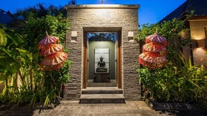 A stone entrance with a statue, surrounded by lush greenery and decorative umbrellas. - 5BR Private Villa near Seminyak (Badung)