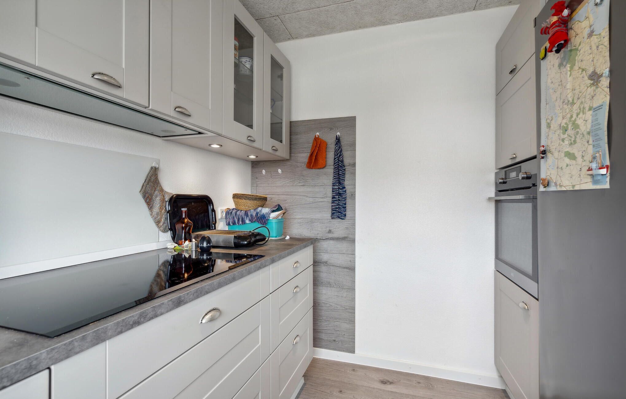 A compact kitchen with white cabinets, a black countertop, and a grey refrigerator.