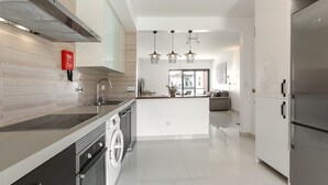 A modern kitchen with a built-in washer and dryer, stainless steel appliances, and a central island. - Baleal Deluxe Flat - Shared pool (Peniche)