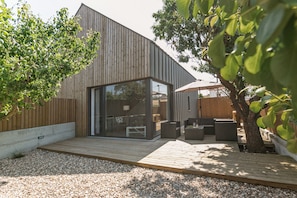 A modern house with a wooden deck, a glass door entrance, and outdoor seating.